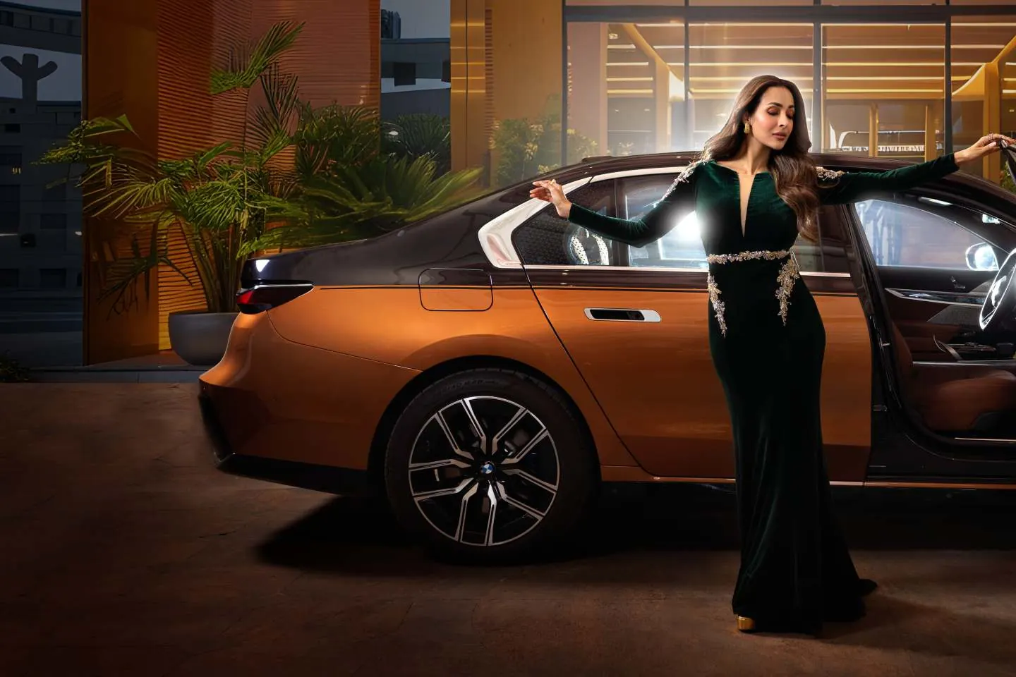 Malaika Arora in green velvet beside a copper saloon car